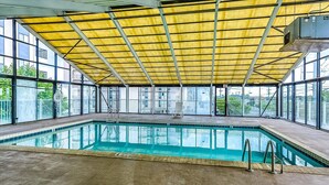 Une piscine intérieure dotée d’un toit jaune, de murs en verre transparent et d’un poste de surveillance pour le sauveteur.