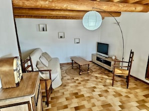 Una sala de estar con un sofá, una mesa de centro de madera, un mueble para televisión y un banjo.