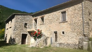 Edificio de piedra con una escalera que conduce a una puerta, rodeado de césped.
