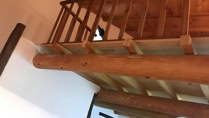 Una escalera de madera con barandilla y vista al piso superior.
