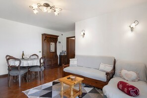 A living room with a dining table, chairs, a sofa, and a small wooden table.