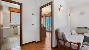 A bedroom with a wooden bed, a sofa, a radiator, and a clock on the wall. - Apartment 'Maison Du Soleil - Bien-être' with Mountain View, Private Terrace and Wi-Fi (Saint-Vincent)