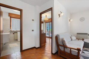 A bedroom with a wooden bed, a sofa, a radiator, and a clock on the wall.