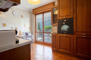 A kitchen with wooden cabinets, a built-in oven, a refrigerator, and a window with a view of greenery.
