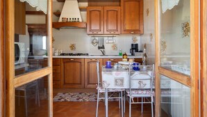 A kitchen with wooden cabinets, a dining table with chairs, and a hanging light fixture. - Apartment 'Maison Du Soleil - Bien-être' with Mountain View, Private Terrace and Wi-Fi (Saint-Vincent)