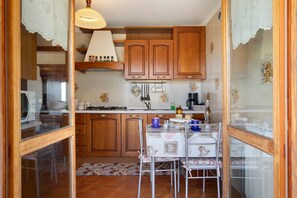 A kitchen with wooden cabinets, a dining table with chairs, and a hanging light fixture.