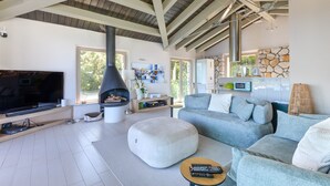 A modern living room with a fireplace, a large TV, and a cozy seating area.