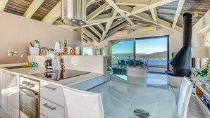 A modern kitchen with a glass island, stainless steel appliances, and a large window overlooking a scenic view.