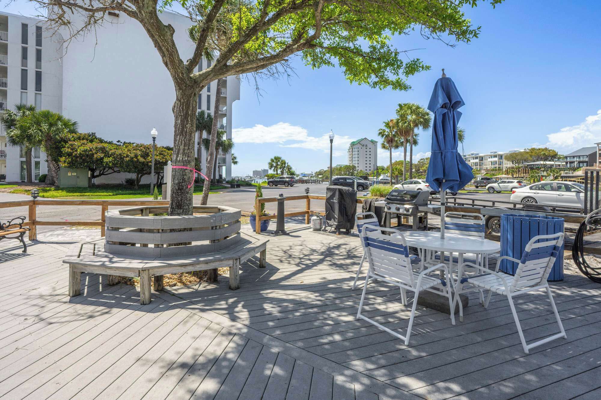 An outdoor seating area with wooden tables and chairs, a covered table, and a tree.
