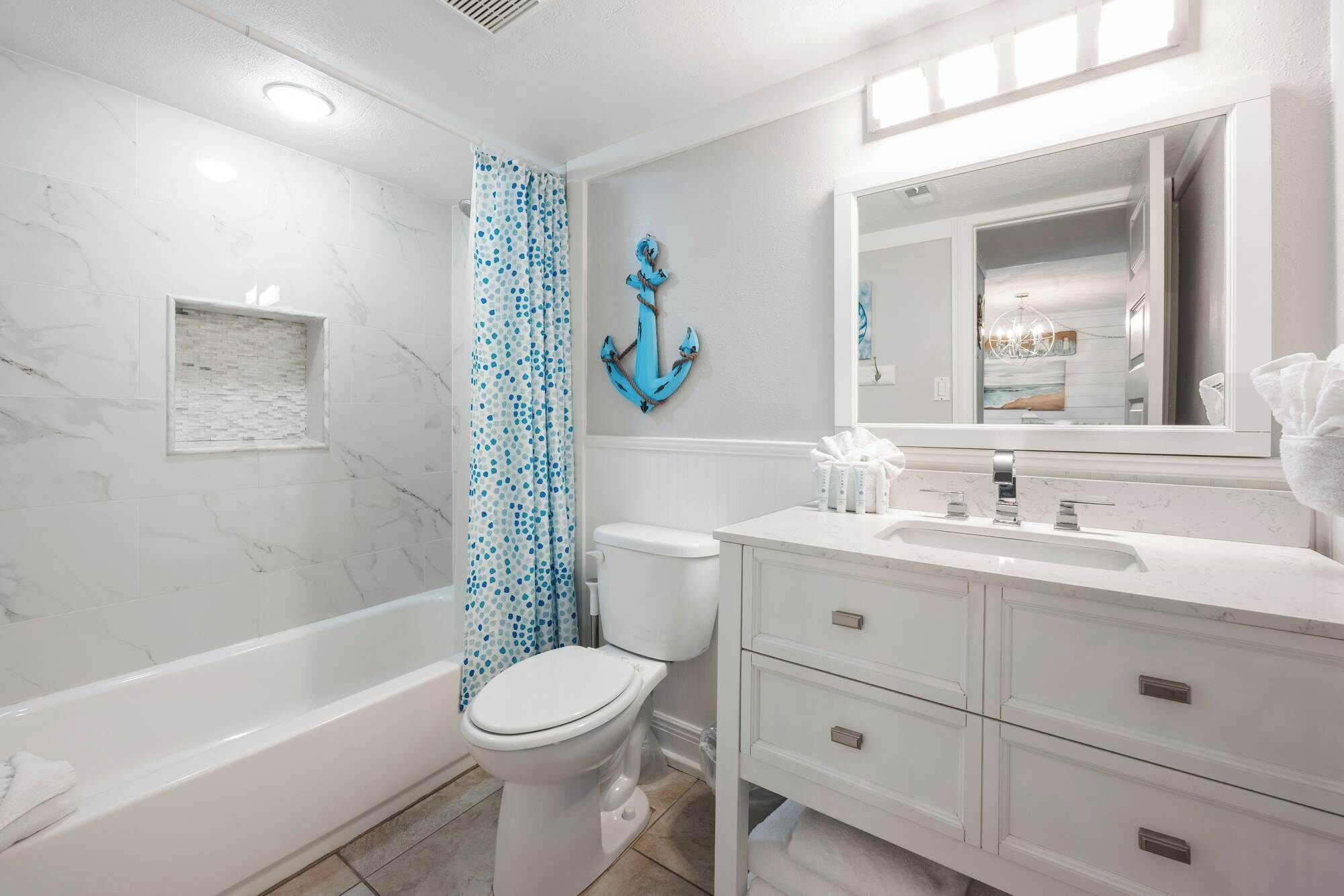 A bathroom with a bathtub, toilet, and vanity with a mirror.