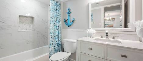 A bathroom with a bathtub, toilet, and vanity with a mirror.