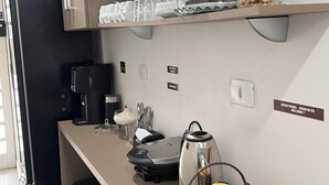 Uma cozinha com cafeteira, chaleira e uma cesta de frutas no balcão.