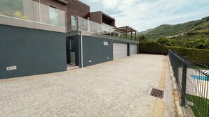 Un edificio moderno con un camino de entrada pavimentado, un garaje cubierto y vistas a un paisaje montañoso.