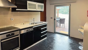 Una cocina moderna con armarios negros, un lavamanos de acero inoxidable y un horno.