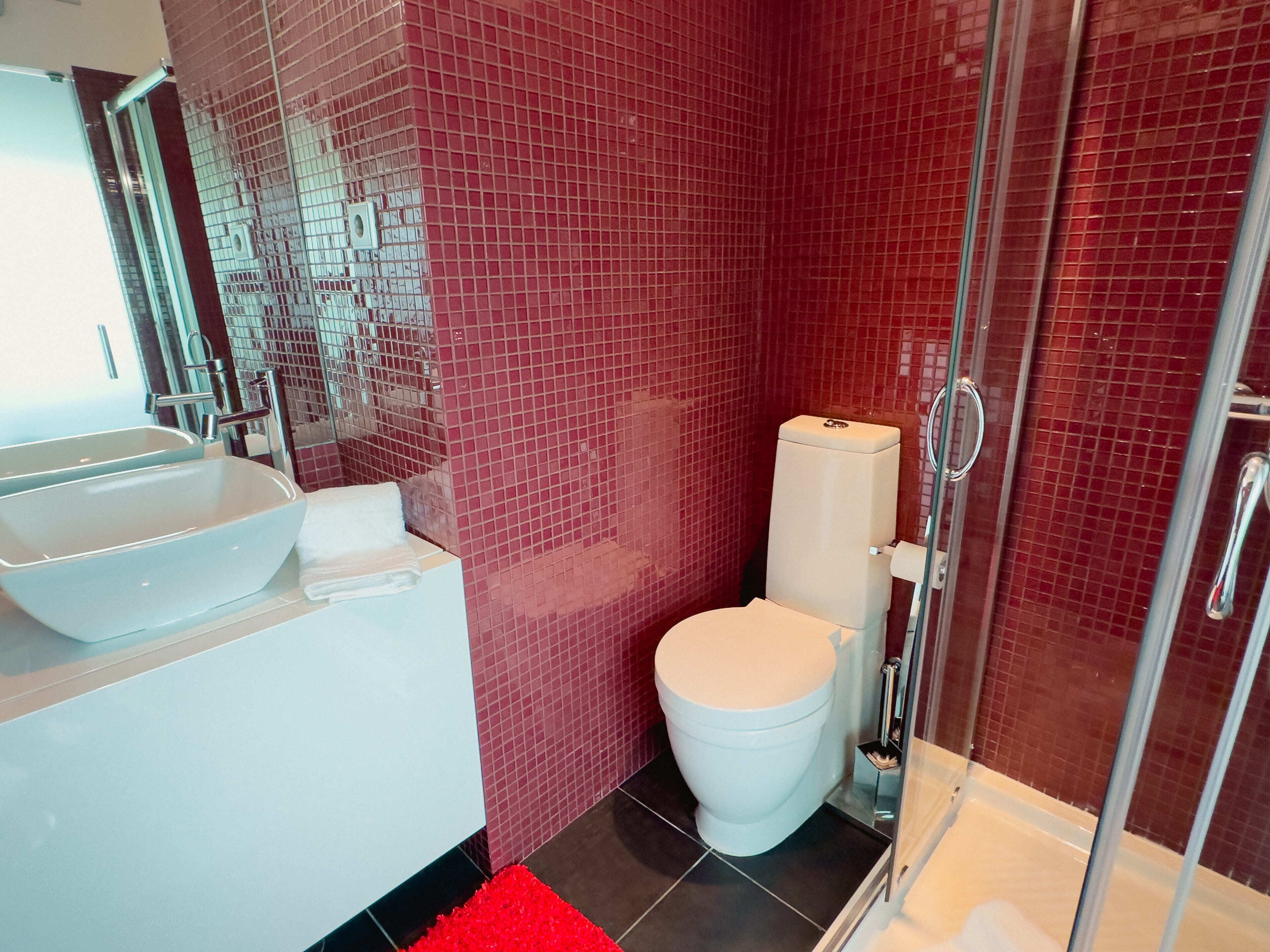 A bathroom with a white sink, a toilet, and a glass shower enclosure.