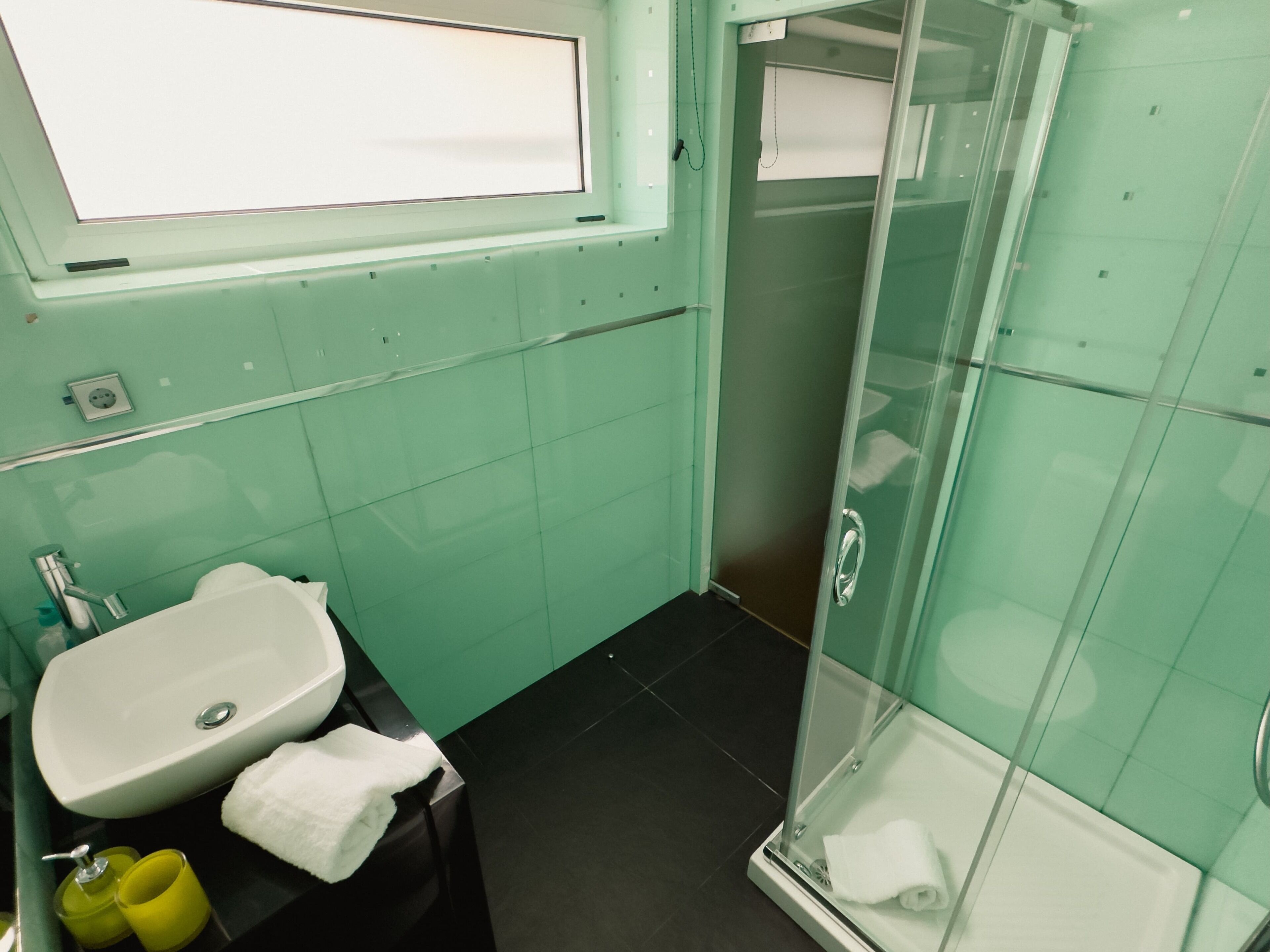 Un baño con lavamanos, espejo y cabina de ducha de vidrio.