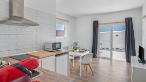 Cozinha moderna com micro-ondas, eletrodoméstico vermelho e painel de azulejos branco.
