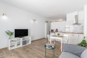 A modern living room with a flat-screen TV, a sofa, a dining table with chairs, and a kitchen area with white cabinets and a microwave. - Vacation 'El Rincón De Agustín I' with Mountain View, Private Terrace and Wi-Fi (Macher)
