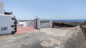 Una proprietà costiera con ingresso carrabile, un patio con tegole rosse e vista mare.
