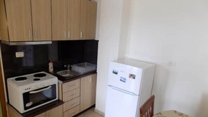 A compact kitchen with wooden cabinets, a white refrigerator, a built-in oven, and a sink. - 25 meters from beach 1 (Himarë)