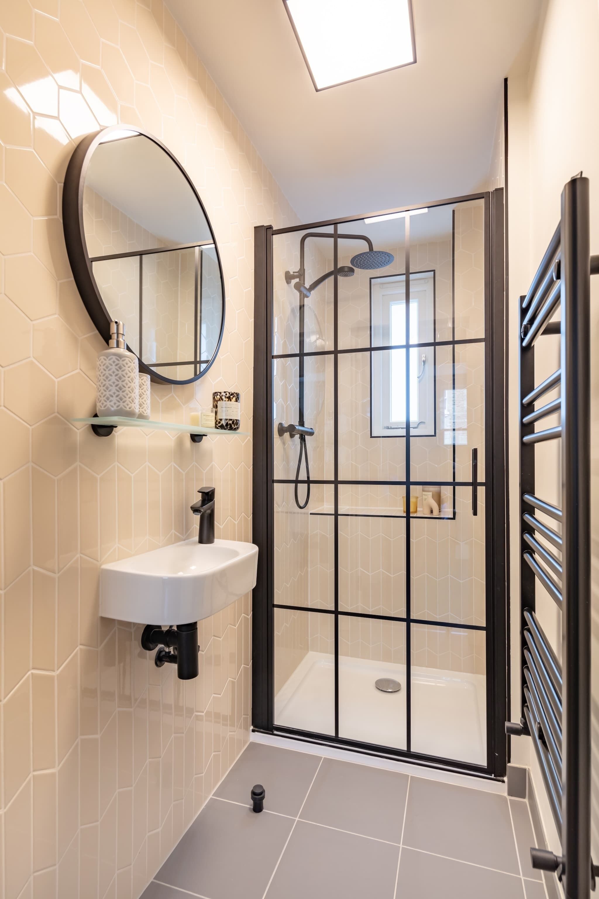 Une salle de bain moderne avec une douche à parois de verre, un lavabo blanc et un miroir.