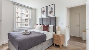 A bedroom with a bed, a nightstand, a window, and a door.