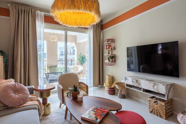 Un salon moderne doté d’un grand téléviseur, de sièges confortables et d’un balcon offrant une vue agréable.