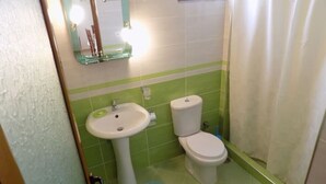Et badeværelse med vask, toilet og bruseforhæng.