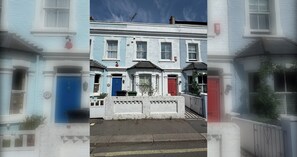 A row of terraced houses with distinct front doors, a central entrance, and a small garden area.