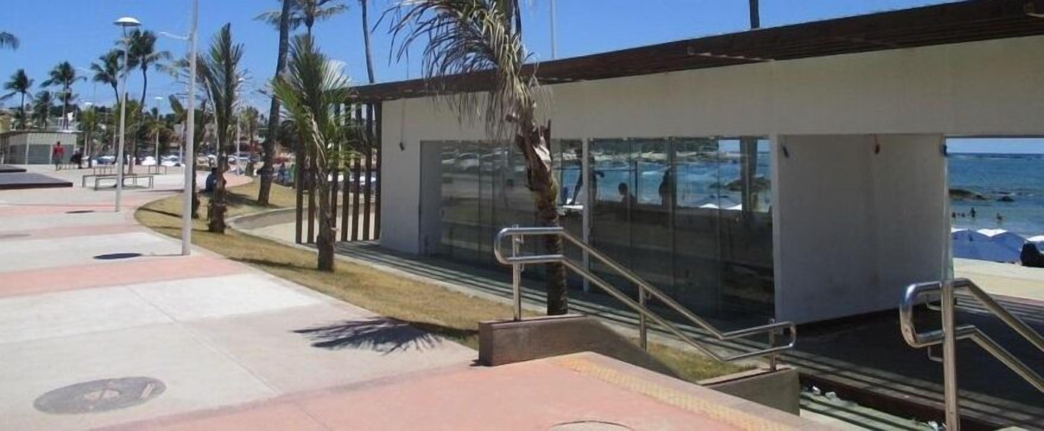 A modern building with a glass facade overlooking a beach.
