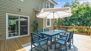 A deck with a table and chairs, a large umbrella, and a wooden railing. - Walk to the stadium! - Lighthouse on Glenwood (Annapolis)