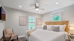 A bedroom with a large bed, a ceiling fan, and two windows with blinds. - Walk to the stadium! - Lighthouse on Glenwood (Annapolis)