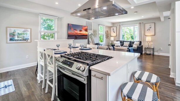 A modern kitchen with a central island, stainless steel range hood, and a built-in oven. - Walk to the stadium! - Lighthouse on Glenwood (Annapolis)