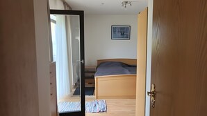 Ein Flur, der in ein Schlafzimmer mit einem Bett, einer Deckenleuchte und einem gerahmten Bild an der Wand führt.