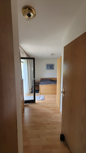 Un pasillo que conduce a un dormitorio con cama, una lámpara en el techo y un cuadro en la pared.