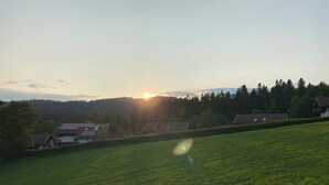 Ländliche Landschaft mit einem Feld, Häusern und einem Sonnenuntergang.