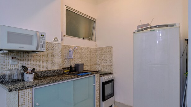 Una cocina pequeña con microondas, estufa y refrigerador.