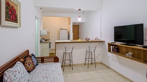 Un espacio habitable compacto con cama, televisión, kitchenette y comedor.