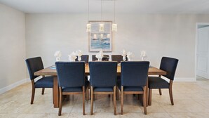Un coin repas avec une table en bois et six chaises, un tableau encadré au-dessus de la table et une porte blanche sur la droite.