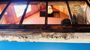 A wooden interior with a red woven basket hanging from the ceiling, a ceiling fan, and a view of the outside through a skylight.
