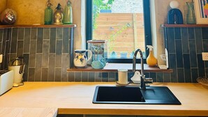 A kitchen with a large window, a hanging light fixture, and a tiled backsplash.