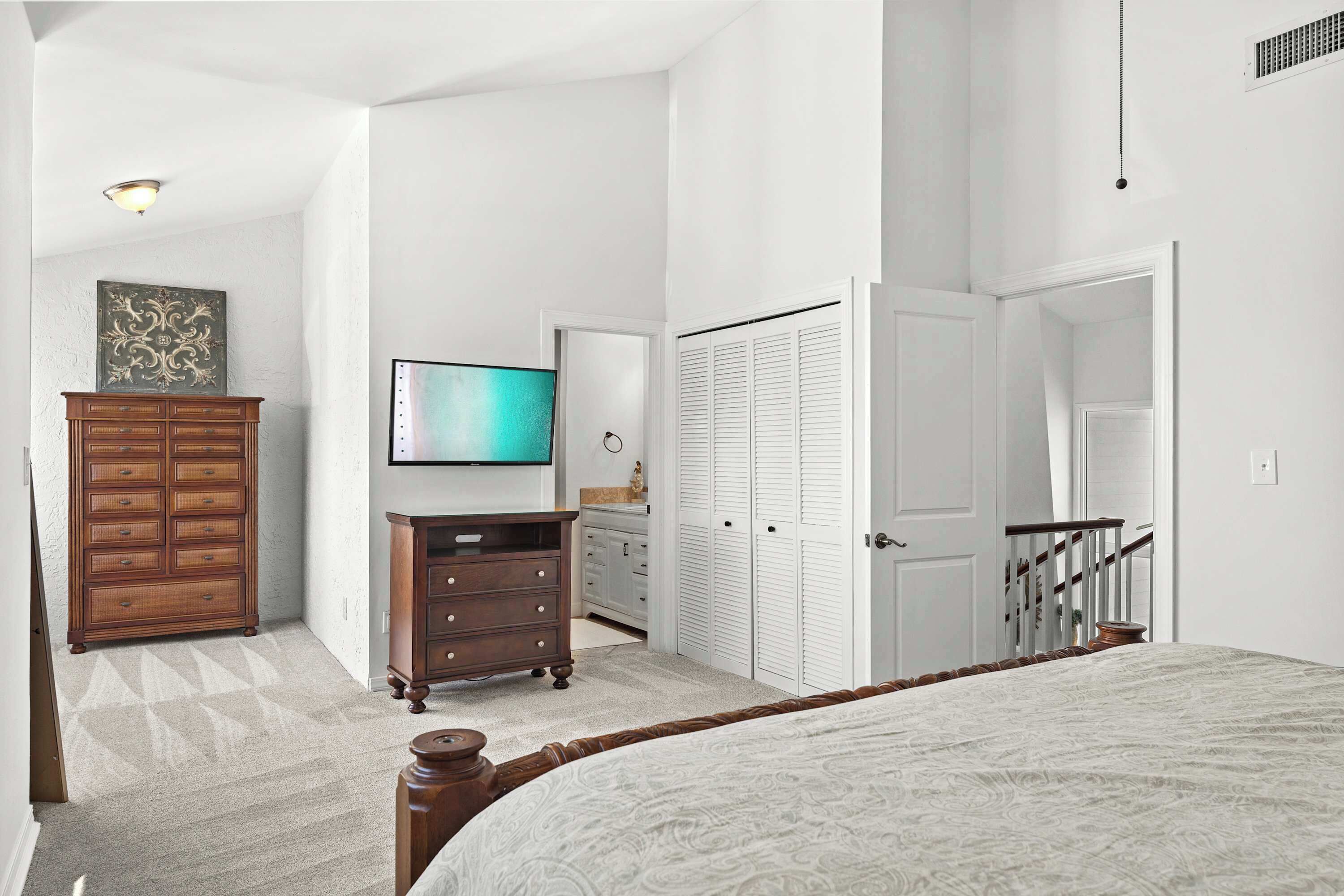 Ein Schlafzimmer mit einem Bett, einem Schminktisch, einem Fernseher und einem Kleiderschrank.