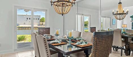A dining area with a glass table, woven chairs, and a chandelier.