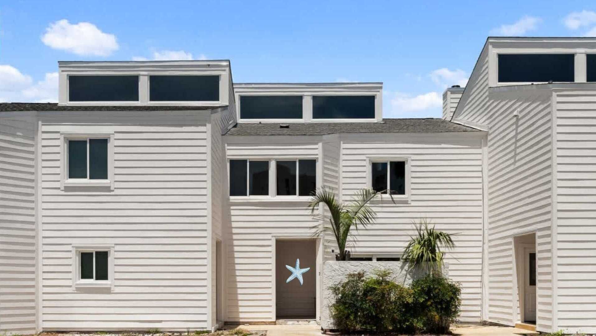 A modern multi-story building with a flat roof, large windows, and a central entrance with a star-shaped door.