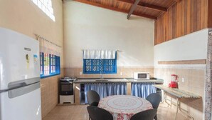 A compact kitchen with a refrigerator, stove, microwave, and a small dining area with a table and chairs.
