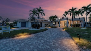 A residential area with paved walkways, palm trees, and houses with garage doors.