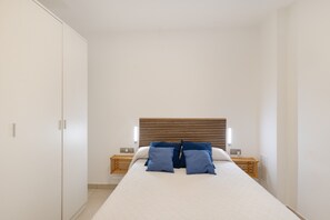 A bedroom with a bed, bedside tables, a wardrobe, and a wooden headboard.
