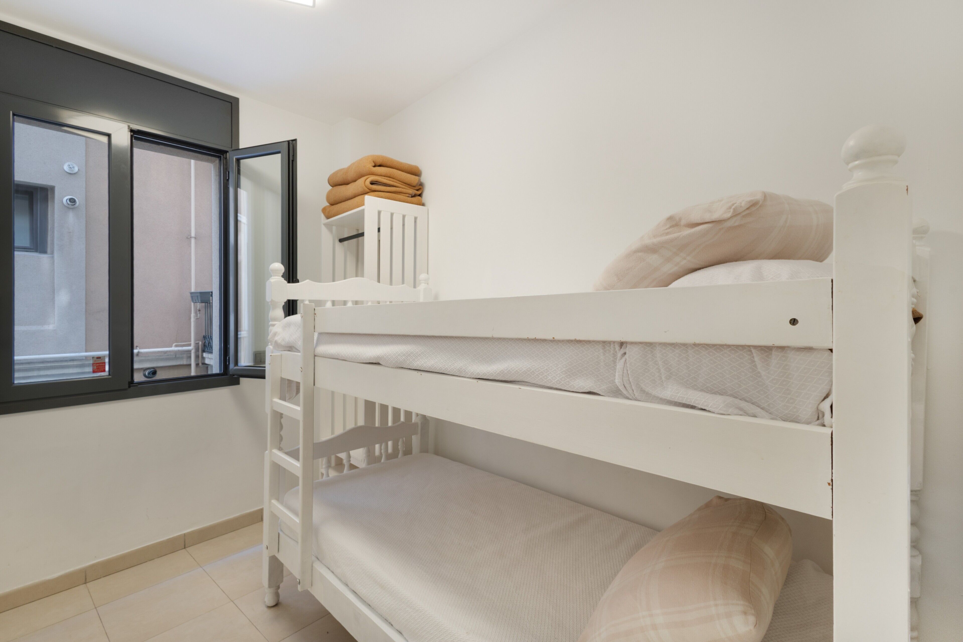 Habitación con literas, una ventana y una pila de toallas dobladas.