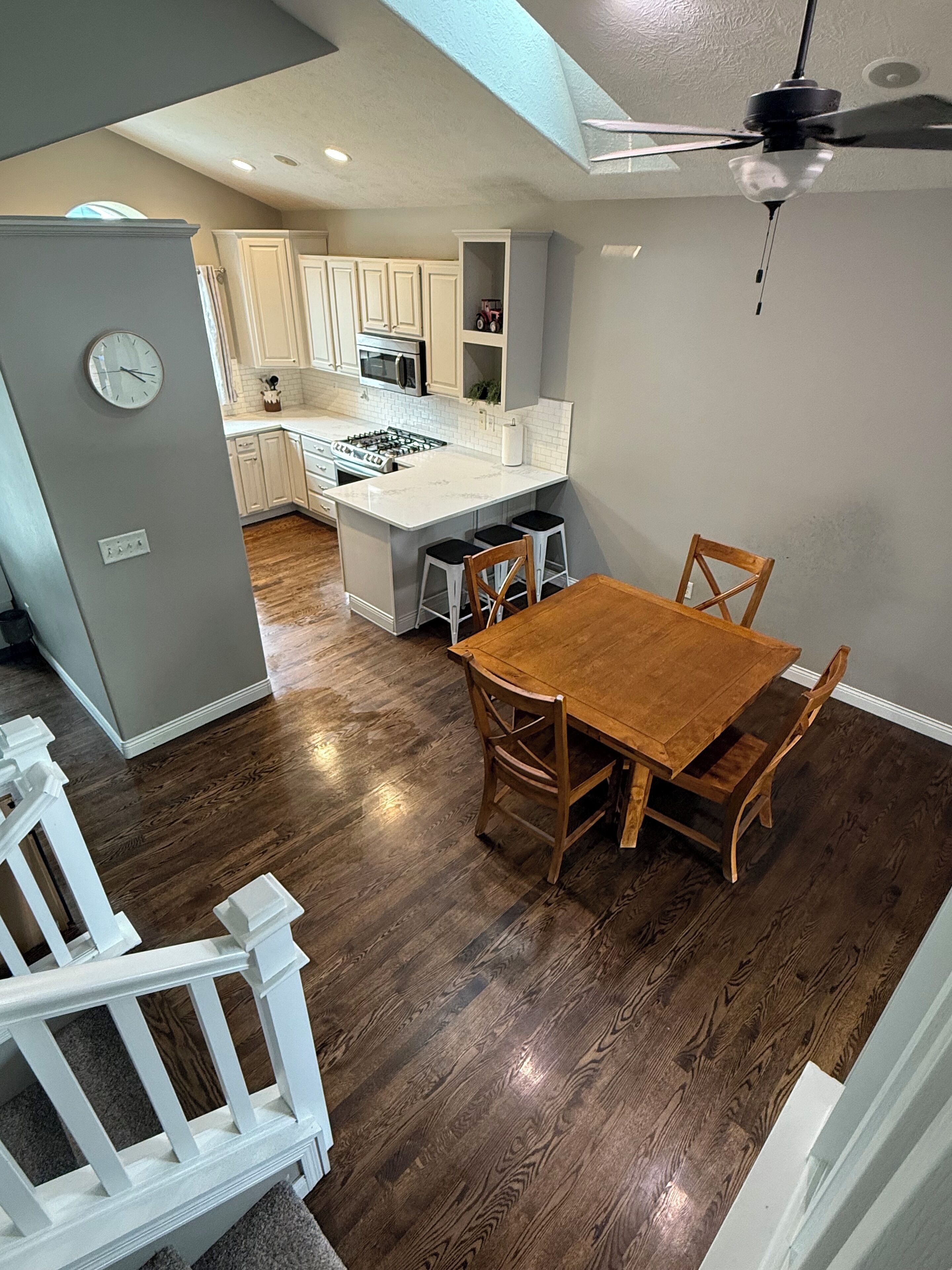 Una cocina moderna con armarios blancos, una isla central y un comedor con mesa y sillas de madera.