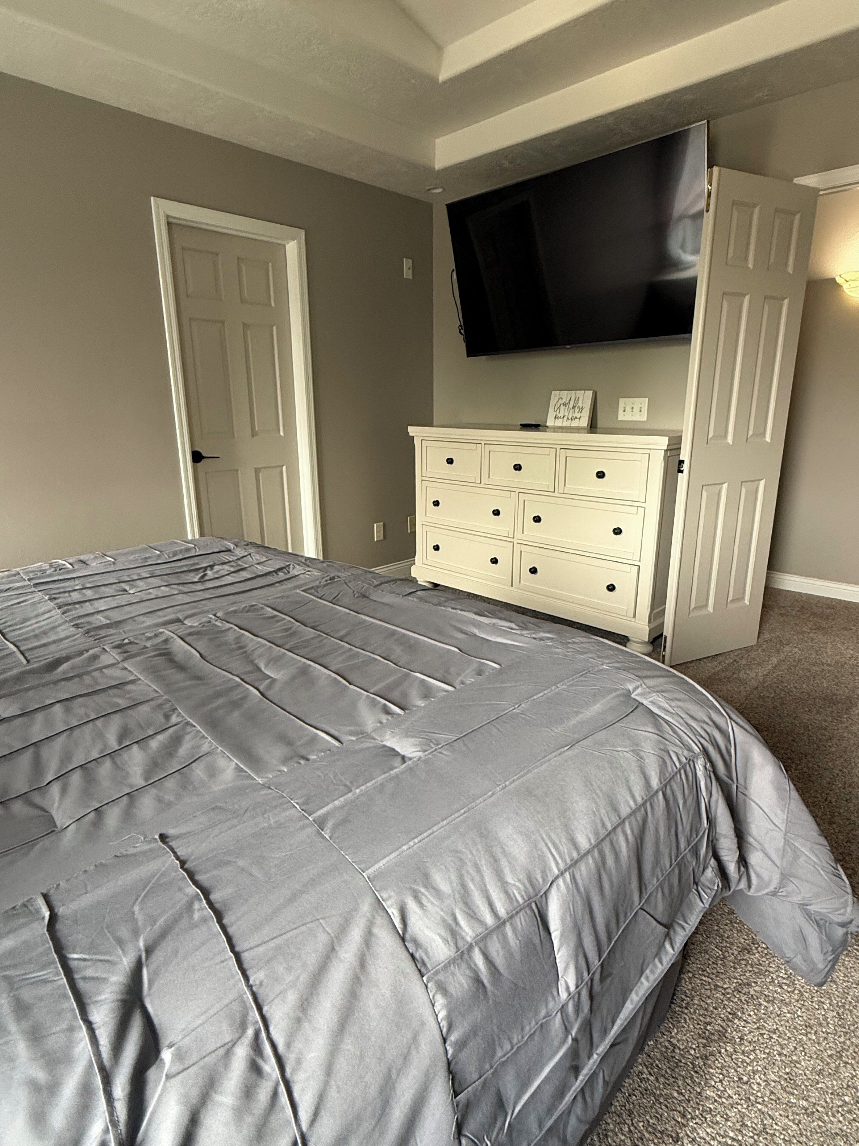 A bedroom with a bed, dresser, and TV.